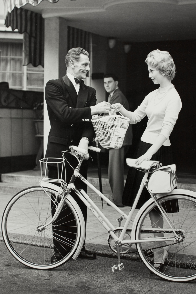 En av de mest populære syklene produsert av Raleigh Industries Ltd, verdens største sykkelfabrikk, vises frem av en kvinnelig eier og en mannlig forhandler. Bildet er tatt i forbindelse med Jakob Øglænd Sandveds besøk på en sykkelmesse og Raleighs sykkelfabrikk i London.
