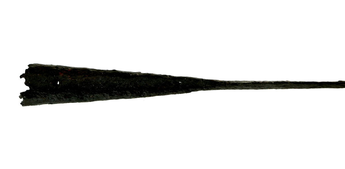 Spydspiss med flatt blad uten forhøyet rygg, kort og med brede sider, og en nærmest direkte overgang til en lengre fal med to naglehull. 
