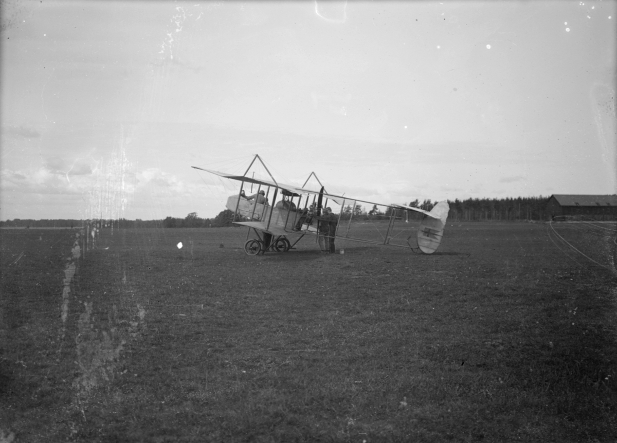Flygplan typ Farman HF 22 (B 2) på flygfältet på Malmen. Förare på plats och tekniker runt flygplanet.