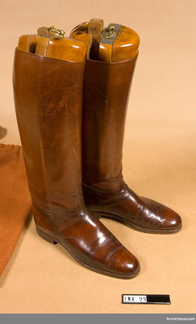 Ridstövlar av brunt läder med randsydd lädersula och gummiklack. Storlek 44.
Med tillhörande skoblock av fernissat trä, samt förvaringspåse i flanell.