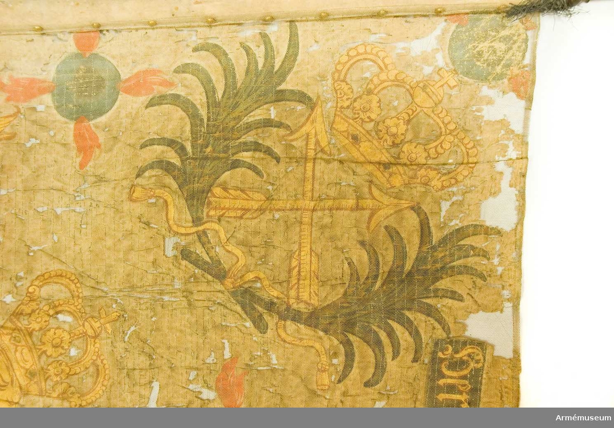Fanduk av vit taft med målade emblem: I mitten tvenne lejon hållande ett spegelmonogram av C. Inuti monogrammet bataljmålning i övervägande blå färger. I nedre hörnen Carl  XII:s krönta namnchiffer inom korslagda palmkvistar, i övre hörnen korslagda dalpilar och öppen krona - Dalarnas sköldemärke - inom palmkvistar. Längs sidorna brinnande fyrkulor. Utmed övre kanten band med inskription på ena sidan: "Herrans och Gidions swärdh" på andra sidan: "Herre tänk på tin David och uppå alt hans Lÿdande". Ornamenten målade i guld, gult och sepia. Fastspikad med gult ylleband(?) och storkupiga, förgyllda mässingsstift, bandet virat och fastspikat fem varv nedom duk på stången. Runt övre och nedre kanten en kort frans omkring stången. Stång av gråvitmålad furu. Stångens färg till största delen bortnött. Spets av förgylld mässing. Holkens vulster är rikt profilerade. Bladet saknas. Holkens längd är 110 mm.