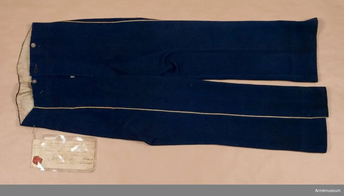 Grupp C I. 
Byxor av mellanblått kläde med gul passpoal och fodrade med grått tuskaftat linne.
Byxor enligt go 30/12 1854.