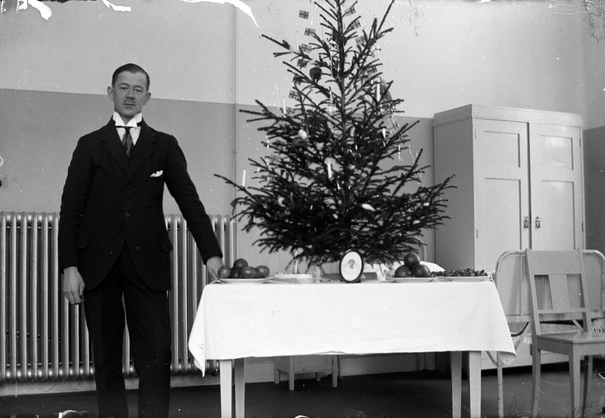 En man står vid ett bord med en julgran på, i bakgrunden element och skåp. Lungkliniken i Eksjö.
