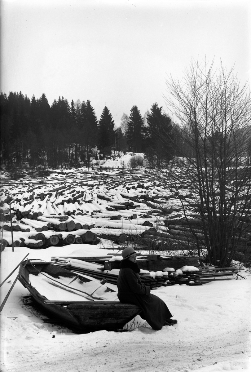 Alma Häger sitter på en eka vid Sjölandet, i bakgrunden en mängd översnöade stockar.