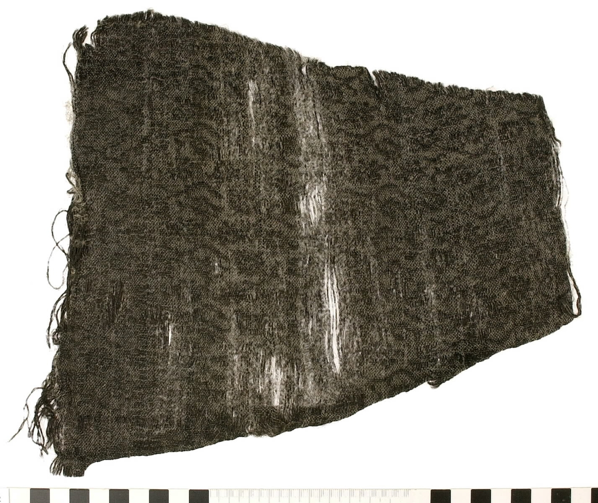 Textil.
8 textilfragment uppdelat på fyndnummer 14647a-e.
Fnr 14647a består av ett fragment av ull vävt i tuskaft.
Fnr 14647b består av två fragment av ull vävda i tuskaft.
Fnr 14647c består av en del av en fåll av silke.
Fnr 14647d består av tre fragment av ull. Det ena är ett vävt band och de andra fragmenten är två halvor av textil som tillsammans bildar en liten rund plätt.
Fnr 14647e är en tygbit med blommönster. "Materialet är svart ull och ljust silke. Det är en ovanlig typ av tuskaftsvävnad med mönsterinslag som ligger obundet mellan tuskaftsinslagen. Mönsterinslagen bildar ett blommönster inom varje rapport som har typisk 1600-talskaraktär. Tillskärning och fållar finns längs alla fyra sidorna. Det är omöjligt att bestämma vad det ursprungligen har varit. Storlek och form anger att det bör ha tillhört något klädesplagg." Looström och Stapf, Tre tusen textilfragment, 1983, s. 29.
Fnr 14647 innehas också av en nål som hör till fyndet.
