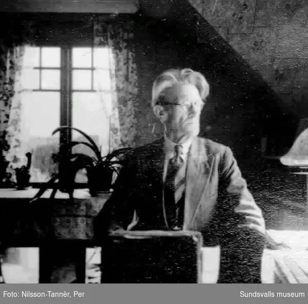Interiörbild. Sågverksarbetaren och författaren Karl Östman (1876-1953) i sin stuga i Valknytt,Sköns sn. Här bodde Karl Östman från 1930-talets mitt till sin död 1953. Stugan blev uppförd genom en insamling.