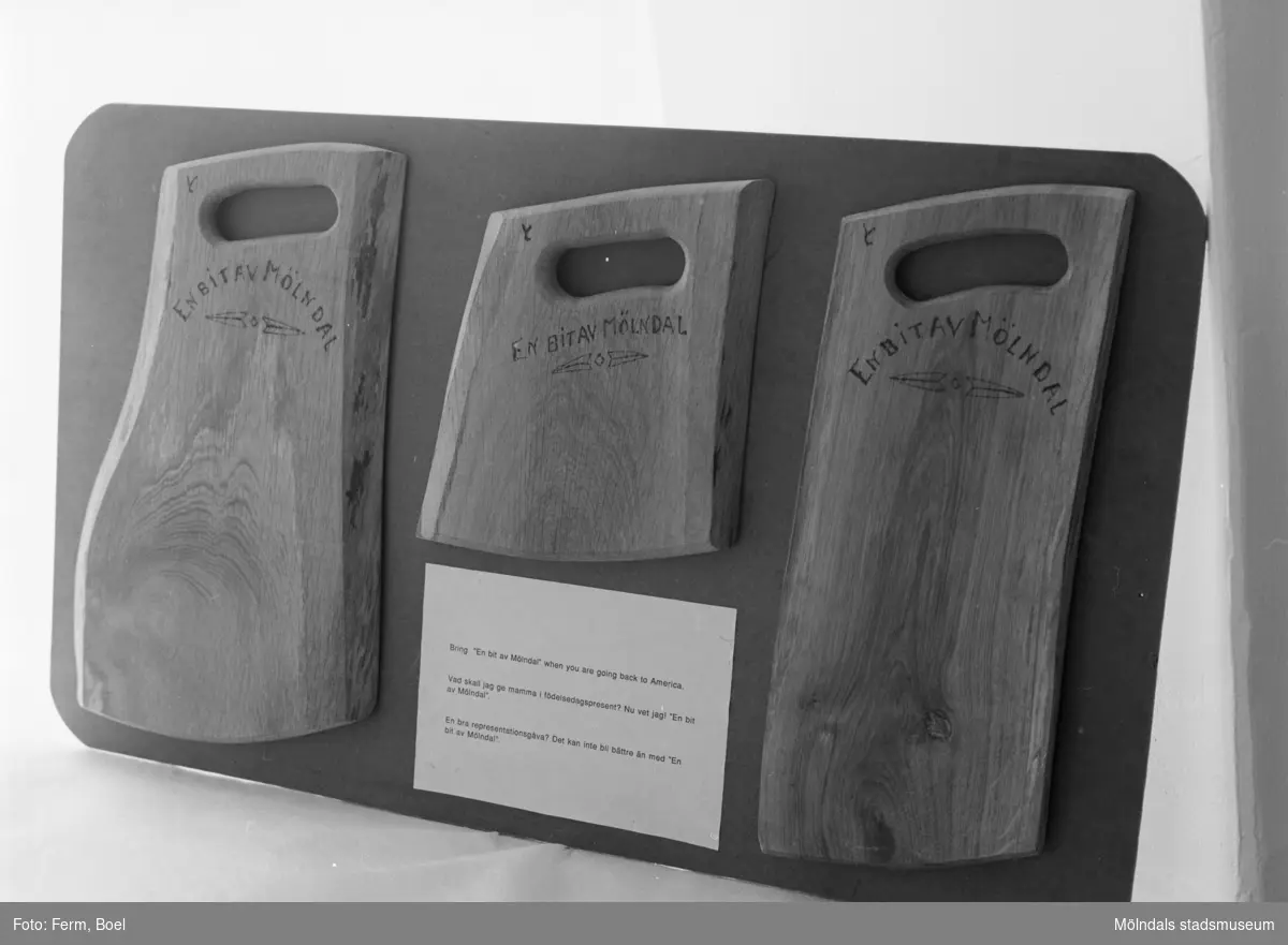 Tre olika slags skärbrädor av trä, inbrända med texten "En bit av Mölndal". Inlämnat förslag till en tävling 1992 om souvenir för Mölndal.