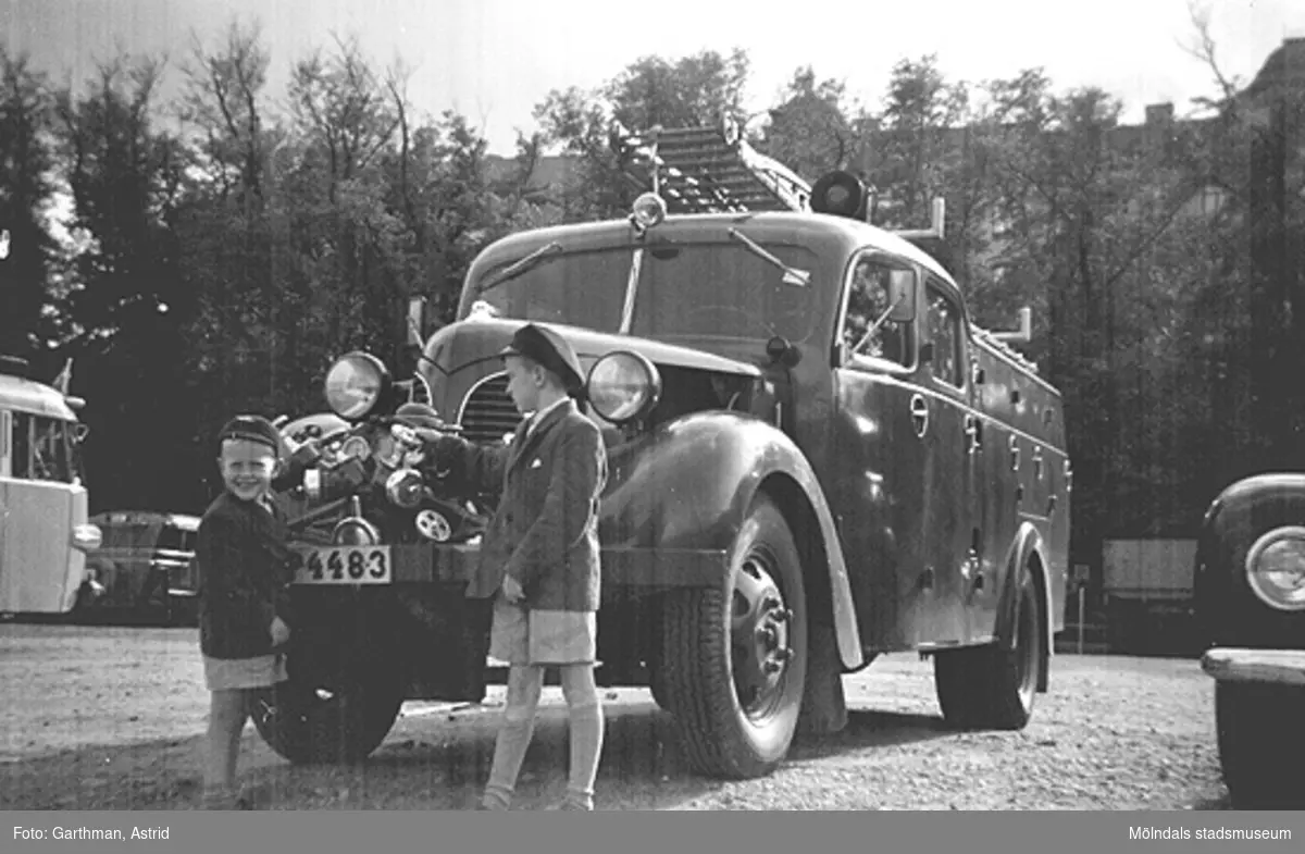 Bröderna Alf och Leif Garthman står vid en brandbil på Heden i Göteborg, 1953-54.