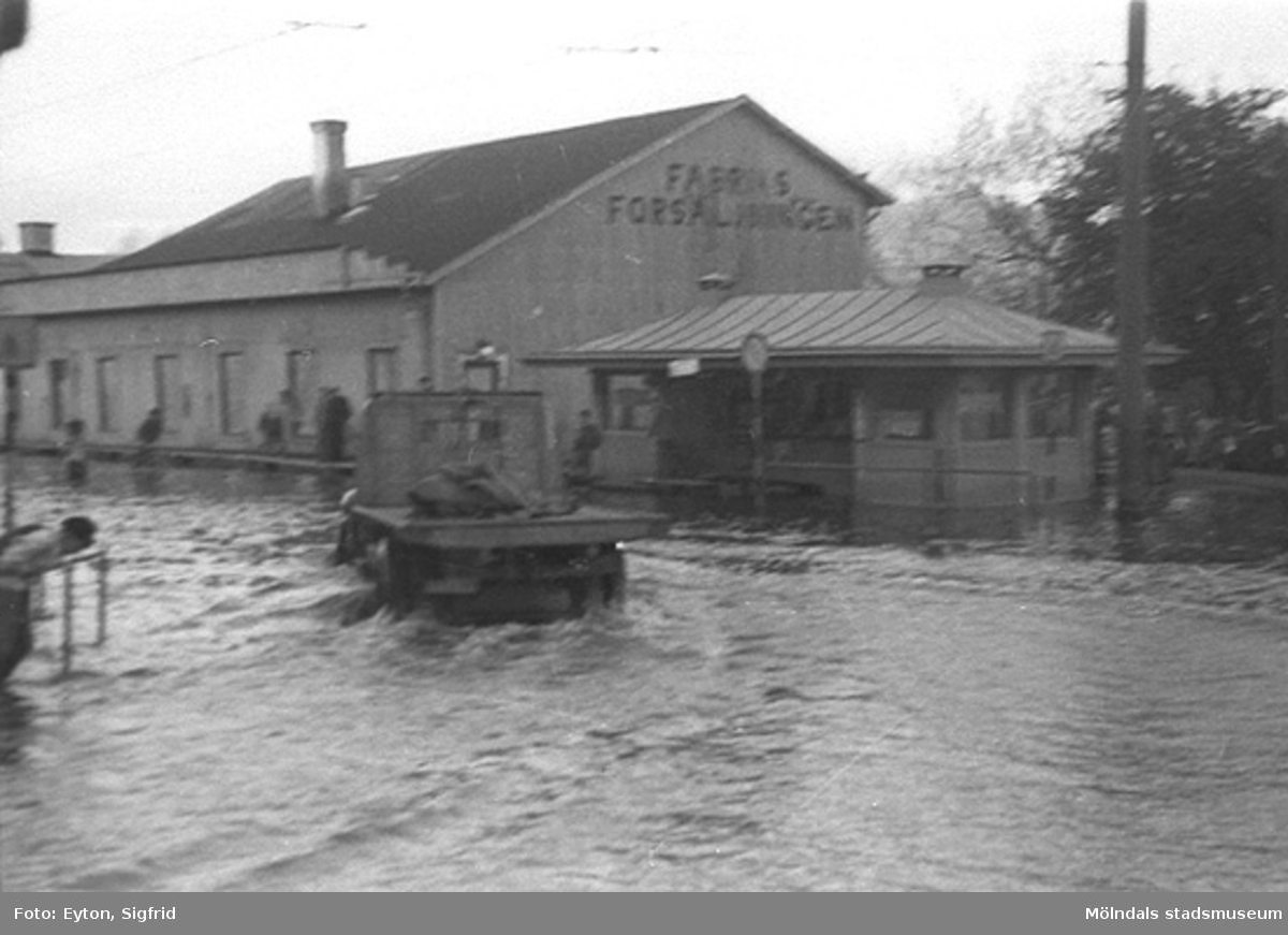 Översvämning vid Fabriksförsäljningen (f. Spårvägshallarna) och Pressbyråns kiosk vid Göteborgsvägen, 1951.
Byggnaderna låg i hörnet mellan Kvarnbygatan och Göteborgsvägen.