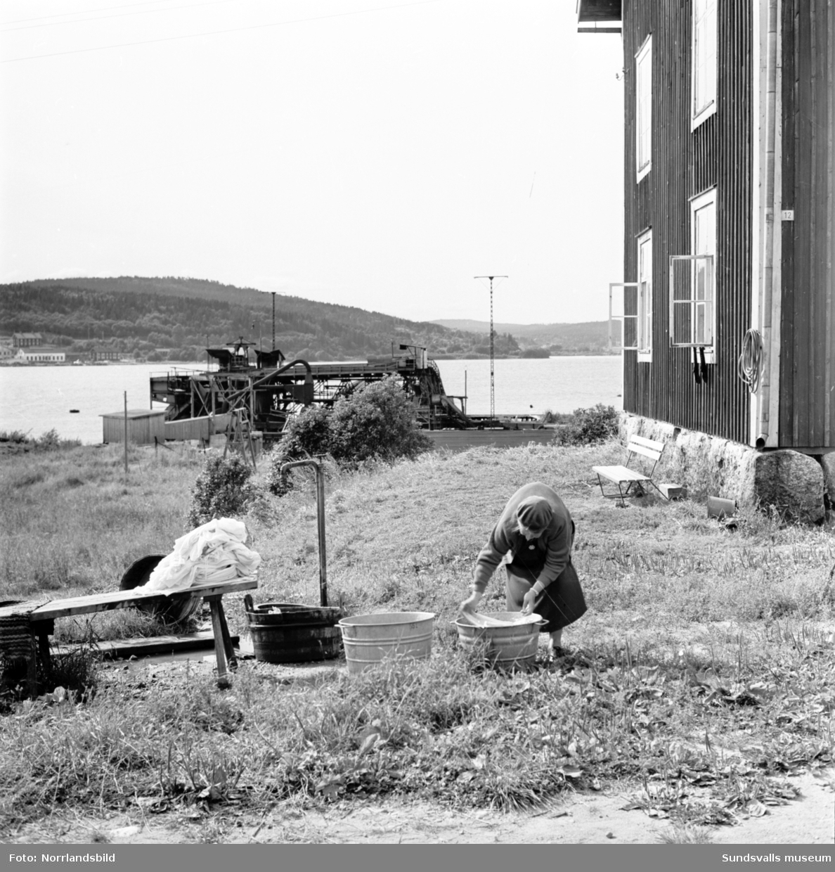 Reportagebilder från Alnö tagna för Expressen. En äldre dam som tvättar utomhus, sågverksbilder, färjan med mera.