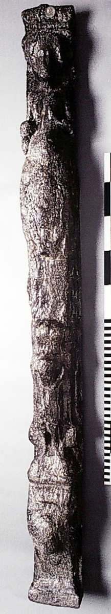 Pilaster föreställande en naken herm, möjligen iförd en huvudbonad av något slag och troligen placerad under ett joniskt kapitäl.
Huvudet är frontalställt. Vänster arm hålls böjd framför bröstet medan höger arm hålls utmed sidan. Nedtill är pilastern prydd med ett stort, bukigt och sköldliknande ornament samt blad- och rullverksbildningar. Längst ner syns en figur, troligtvis en stående putto, bärande en blomsterkorg på huvudet.
Skulpturen är rakt avskuren i bägge ändar. Baksidan är slät och jämn, förutom ett smärre parti av vänster halva, sett från betraktaren, som upptill är nedsänkt.
Skulpturen är kraftigt sliten och nött.

Text in English: Sculpted pilaster with naked Herm, possibly wearing a hat of some kind, standing under an Ionic capital.
The left arm is held bent in front of the chest, while the right is held along the side. The head is shown en face. The lower part of the pilaster is decorated with a large shield-like ornament and leaf and scroll-work formations. At the bottom there is a figure that may be identified as a putto with a flower basket on its head.

The sculpture is cut straight at both ends. The back side is flat and smooth.
The sculpture is badly worn.