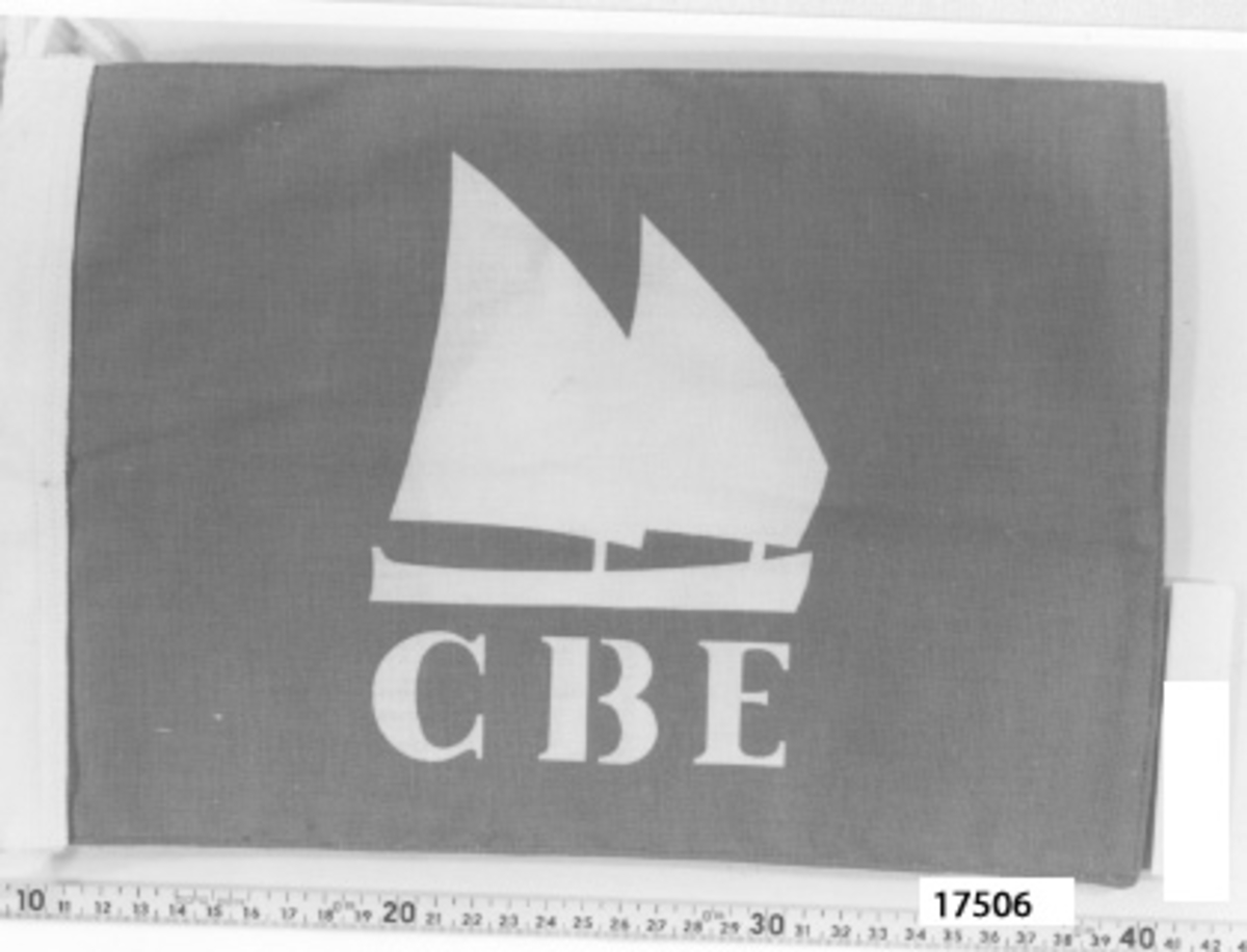Rektangulär vimpel av dubbelt tyg, flaggblå infärgning med motiv och text i utsparat vitt, tvåmastad loggertriggart fartyg, under "C B E". Lik och lina i vitt.