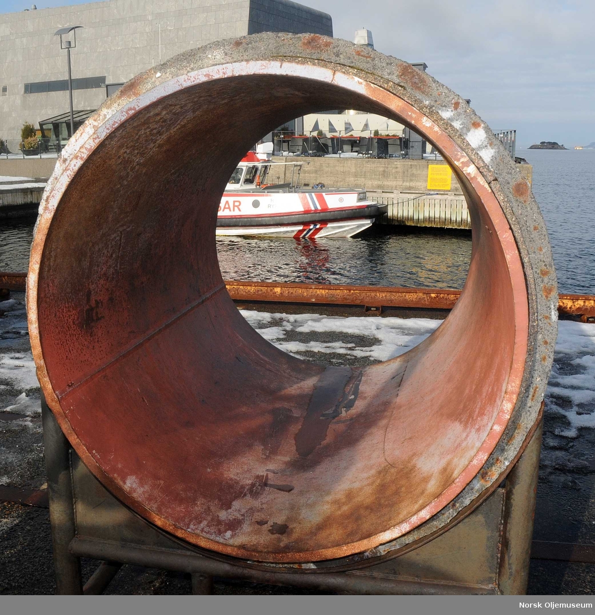 Bit av stålrør belagt med betongkappe.  Rørert er plassert utendørs ved Norsk Oljemuseum.