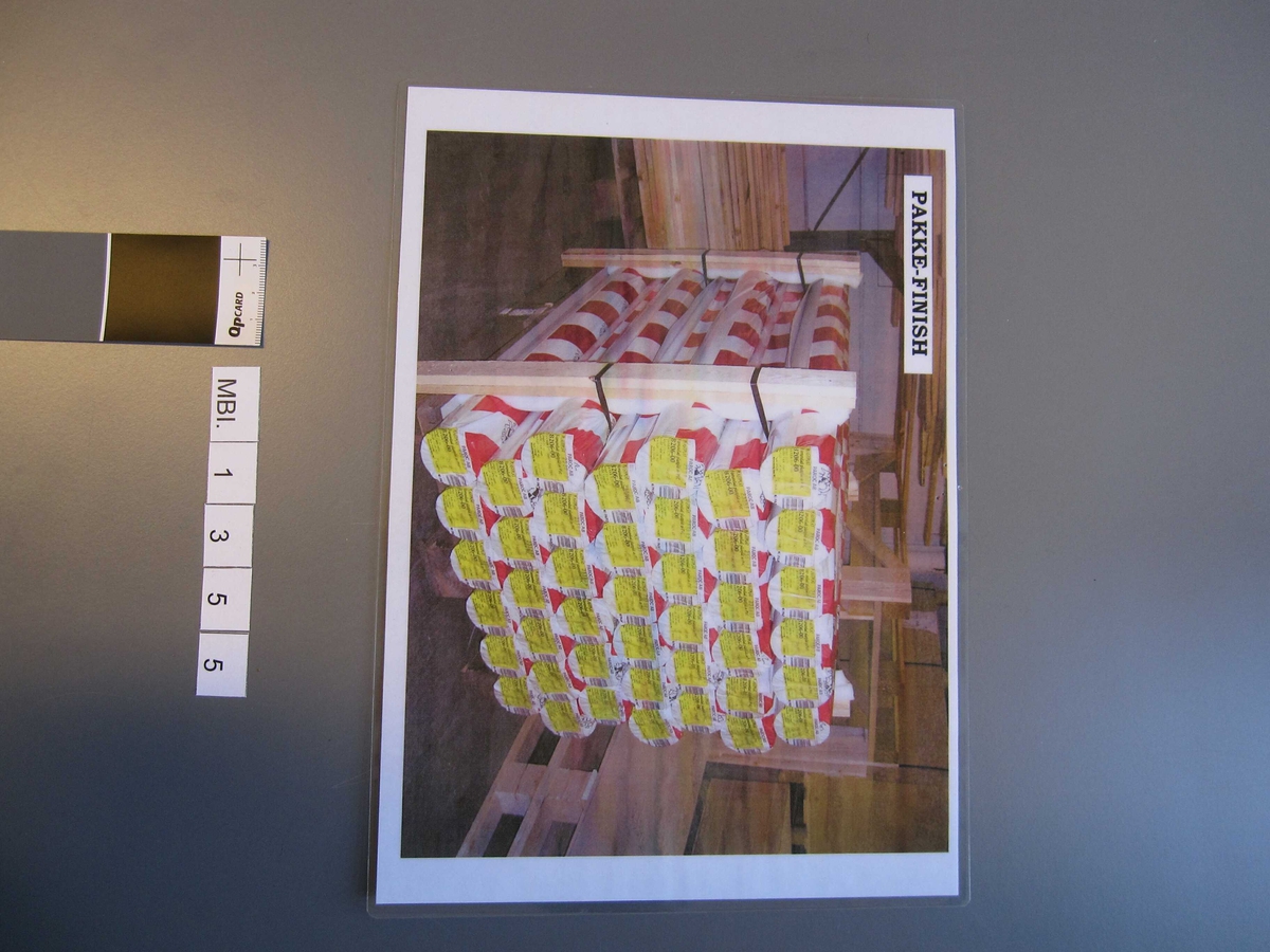 Plakaten viser en pall i lagerlokale stablet med 42 innpakkede ruller krøllfolie.  