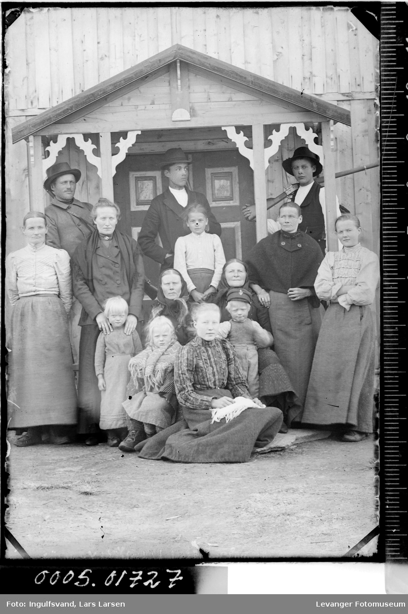 Gruppebilde av syv kvinner, tre menn og fire barn ved et inngangsparti.