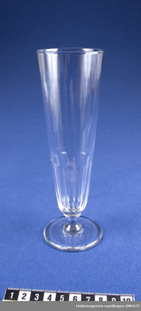 Sett med 7 champagneglass med vannrette riller nederst på klokken. Innsvinging på stetten og med liten for.
Glasset er muligens gammelt. På slutten av det 1800-tallet produserte Hadeland glass med samme form og omtrent samme høyde og kalte det for "seltersglass".