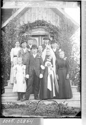 Brudepar med følge ved et inngangsparti.