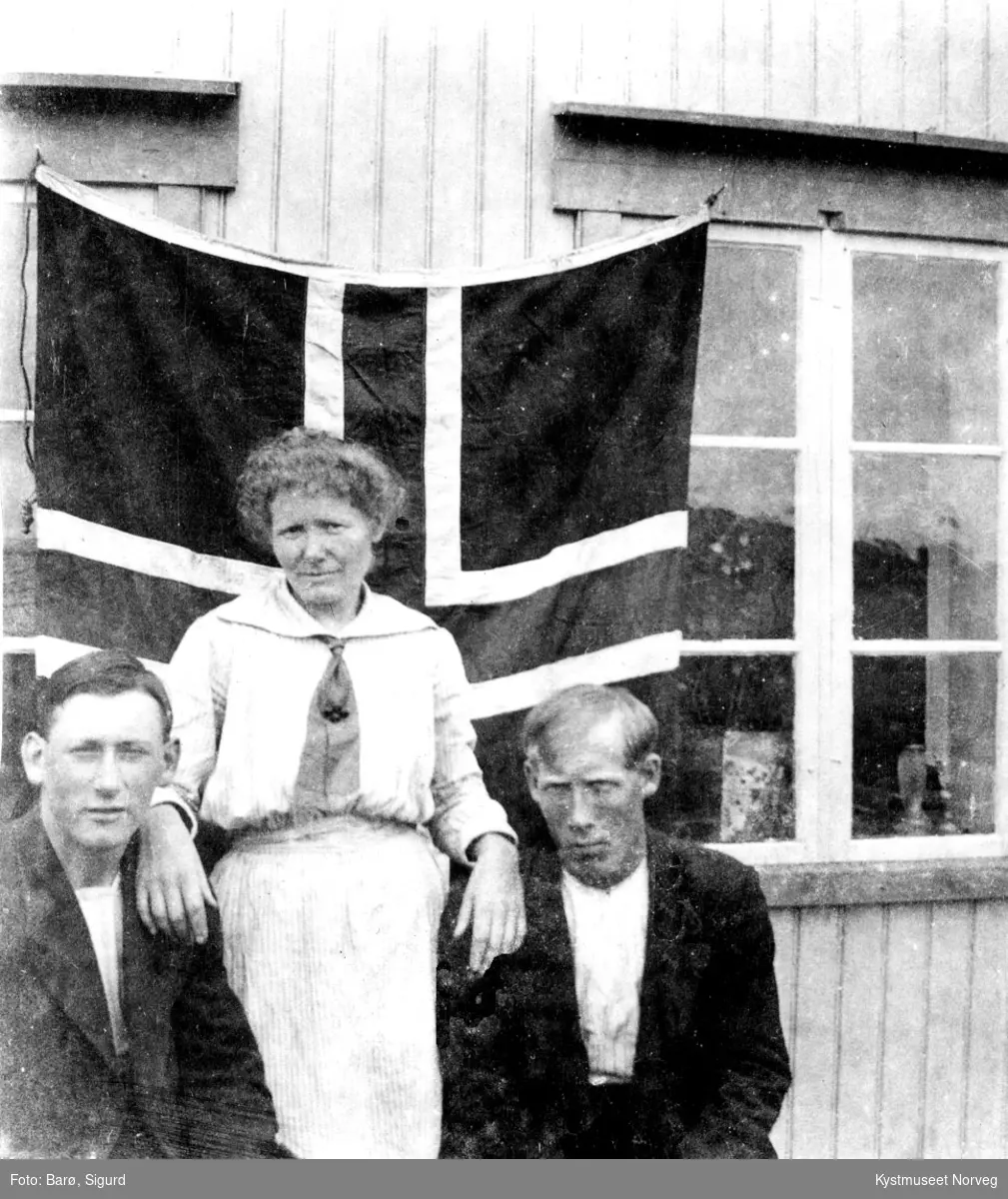 Sigurd Barø, Josefine Vassli og Johan Lennavik foran flaggprydet hus på Versøya i Flatanger