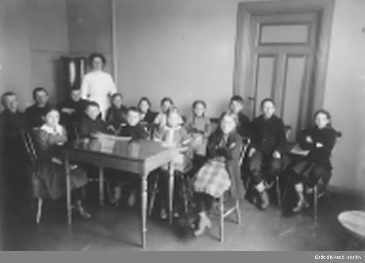 Fra tannklinikken i Sarpsborg ca. 1913-15. Femten barn på venteværelset, og tannlegesøster/assistent i bakgrunnen. Alle barna har kort i hendene. Tannklinikken åpnet i 1913, først i 1923 ble byene forplikta til å holde tannklinikk. 1958 flytta til Kruseløkka.