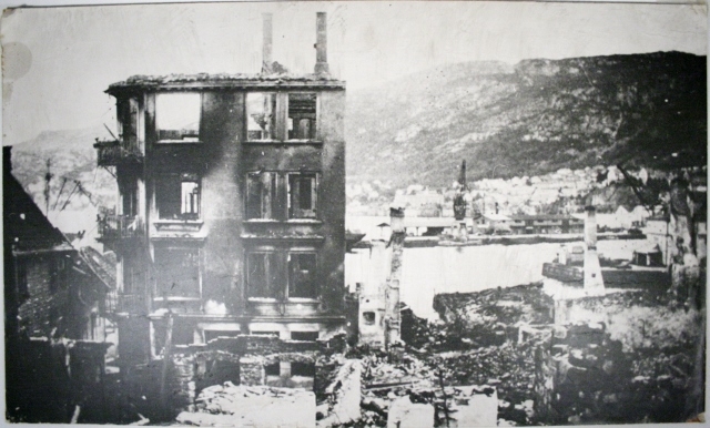 Forstørret bilde på plate fra tidligere utstilling. Bildet viser et bombet området ved en havn.