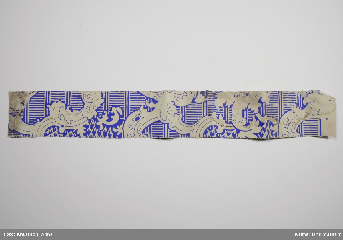 KLM 43790:1. Tapet i papper. Pappersfärgad botten med mönster i ultramarinblått. Datering: 1850-tal.