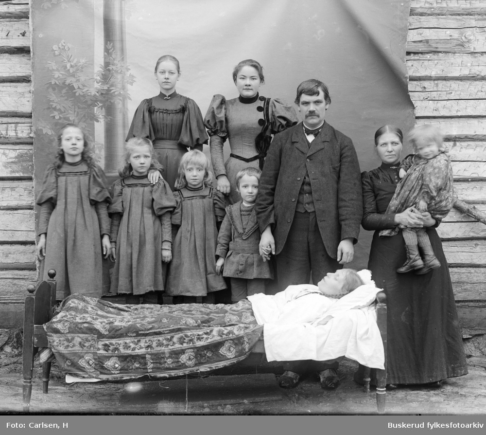 Fmailiegruppe ved en båre.
Hr. Talbø ved sin avdøde datter og sine 7 barn