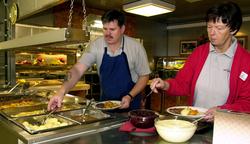 To personer i forpleiningen forsyner seg med middag beståend