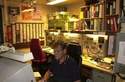 En mann jobber på et kontor med diverse kontrollpaneler, dok