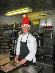 En kokk med nisselue legger bacon i en ovnsform.