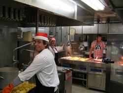 To kokker med nisselue tilbereder og tilbyr mat til ansatte.