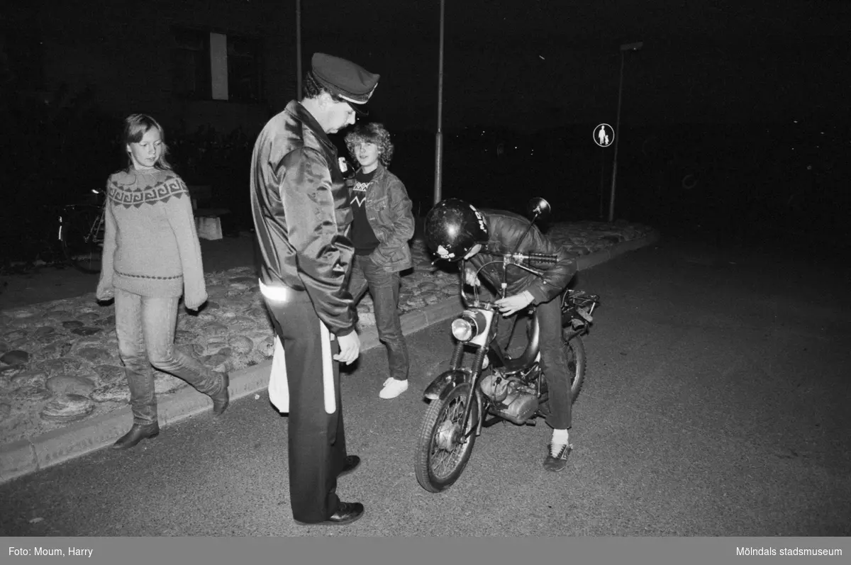 Kvarterspolis Ola Candefors, Batong-Ola kallad, ses tillsammans med några undomar utanför Almåsgården i Lindome, år 1983. "Kvarterspolis Ola Candefors hjälper en mopedist med ljuset."

För mer information om bilden se under tilläggsinformation.