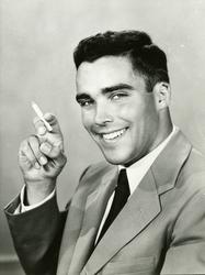 Portrett av mann i dress som røyker en sigarett.