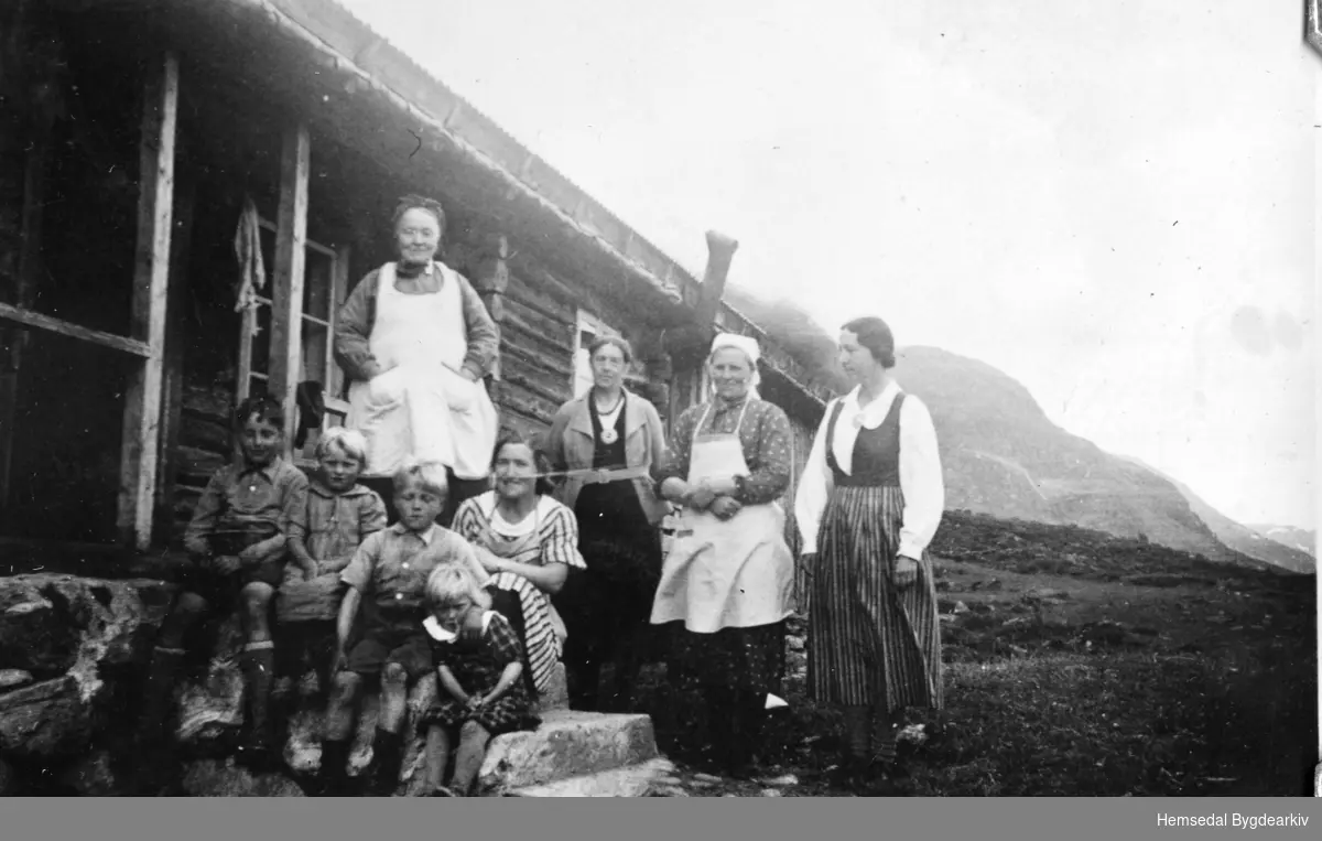 På Heggeslettene (Heggjislettat'n) i Hemsedal, ca. 1940.
Fremst frå venstre: Bygut; Borghild Haugen, fødd 1932; Olav Haugen, fødd 1929; Ingrid Haugen, fødd 1934; Bydame.
Bak frå vesntre: Gunhild Hulbak (1863-1948), fødd Bakke; Bydame; Sigrid Haugen (1891-1958); Bydame.