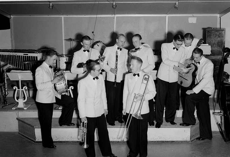 Whispering Band, nio män med musikinstrument.
