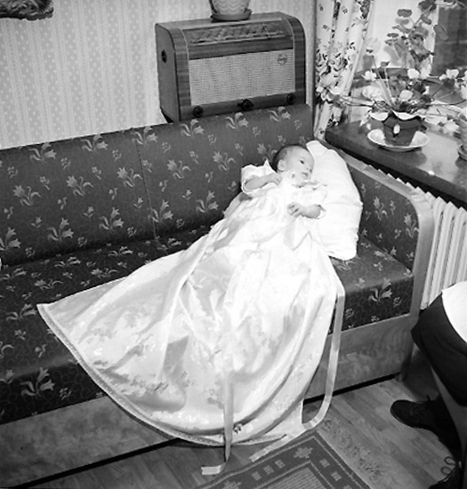 Rumsinteriör, en baby, barndop.
Fru Nils Nilsson