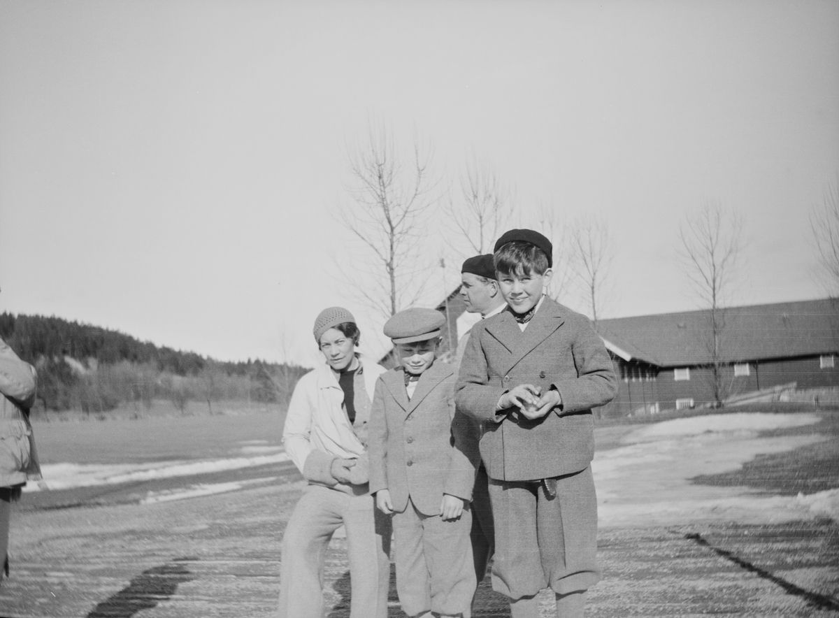 Celina Marie Mathiesen, en mann og to gutter har stilt seg opp for fotografen på gårdsplassen på Linderud gård. Den fremste gutten holder en snøball i hånden.