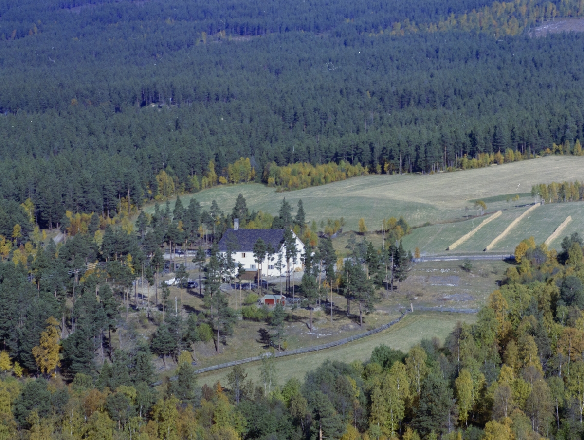 Flyfoto,Skog og jordbrukslandskap med et stort hvitt hus. Det er merket som Frichs Conditori bakeri