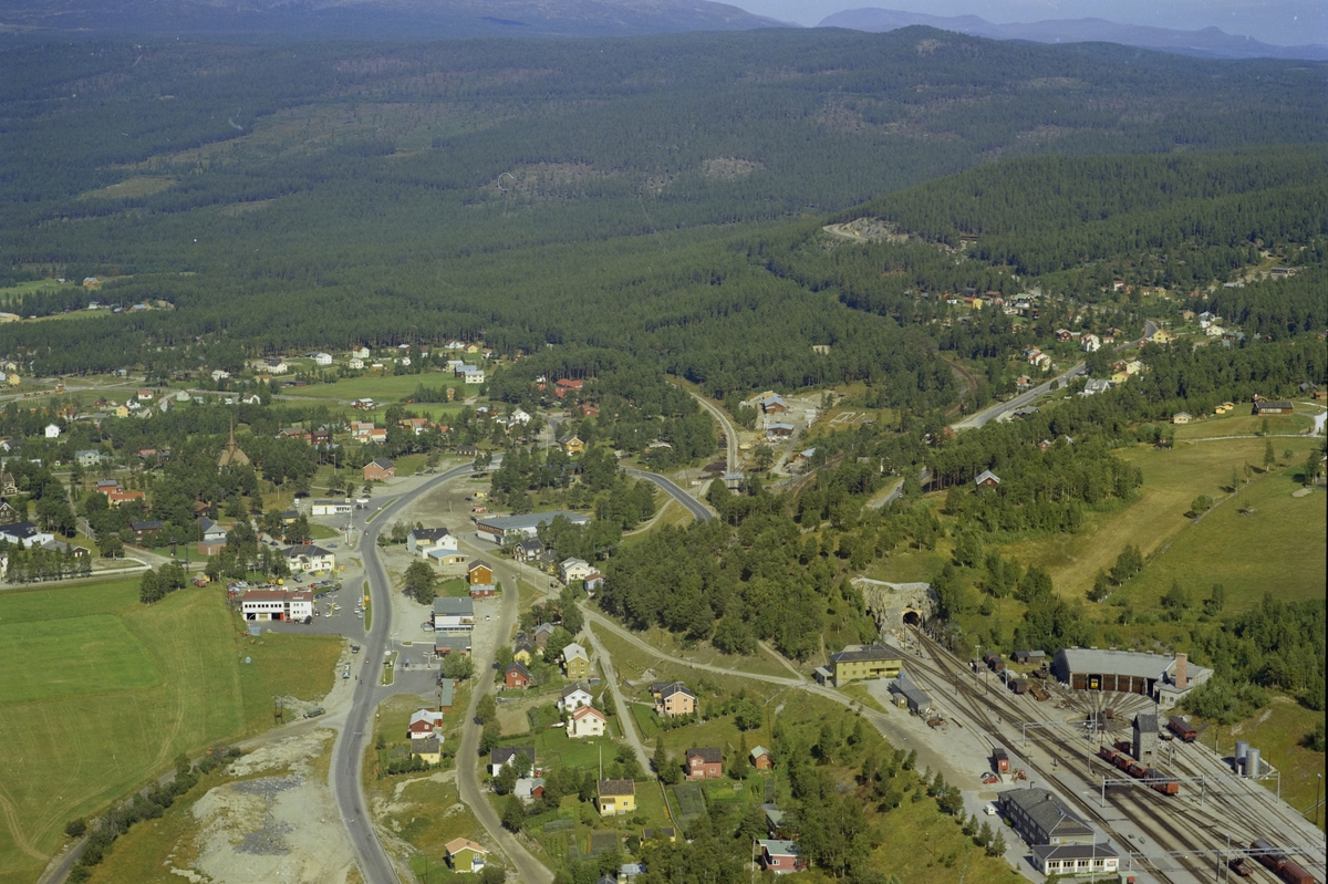 Flyfoto, landskap med tettstedet Dombås og  jernbanestasjon ned til høyre