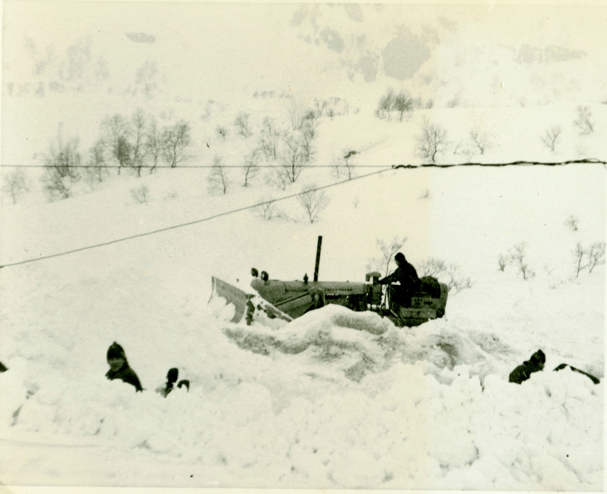 Lastemaskin og buldoser til Brødrene Kaslegard brøyter snø på tippen i Raunalia. Det var 3,5 meter snø der i 1962.Legg merke til lysledningane.Buldoseren går oppå snøen for å skuve vekk det lastemaskina lyftar opp.
Wigger Liahagen arbeidet her i 1962-64