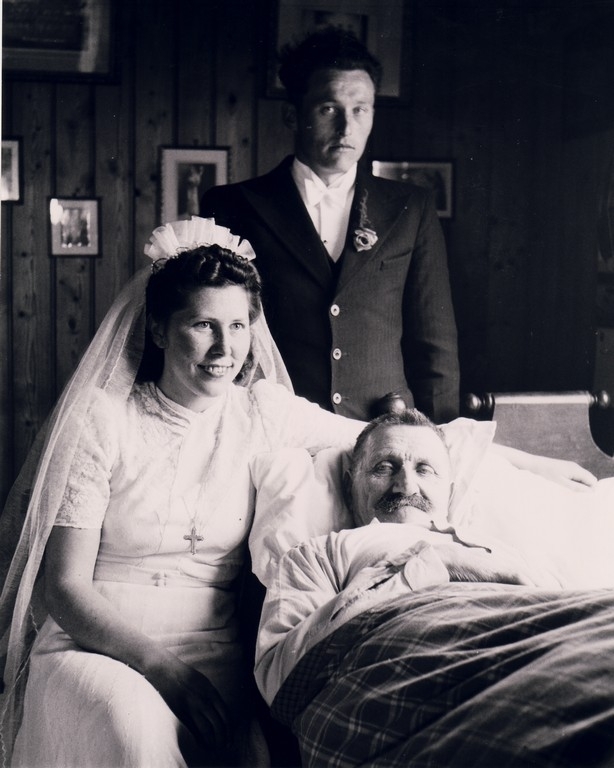 Brudeparet Mildrid f. Søyland (1921 - ) og Trygve Undheim (1917 - ) ved sjukesenga til Karl Søyland (1881 - 1954), far til brura. Han var sengeliggande heime i nær 14 år på grunn av slag.