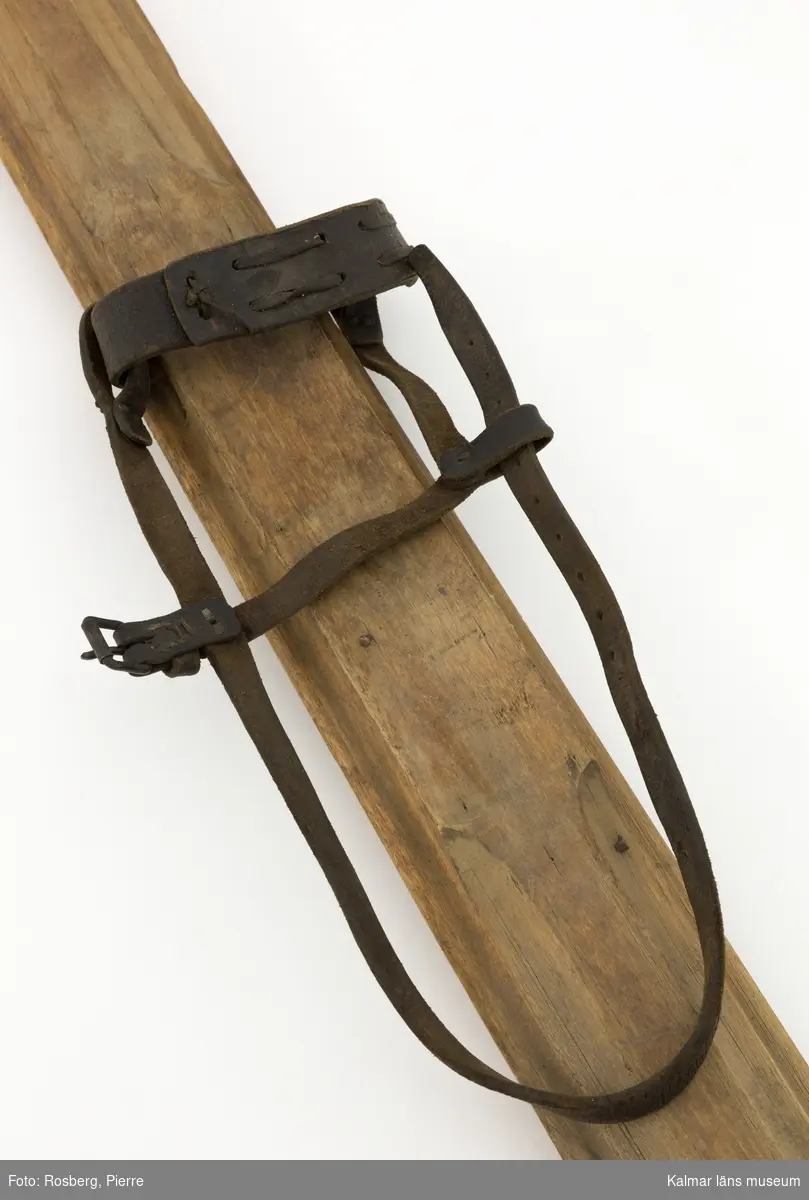 KLM 45694. Skidor, ett par. Av trä med bindning av läderremmar. Spetsig form både fram och bak.