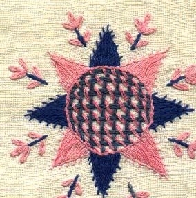 Fyrkantig broderad duk i Hallandssöm. Broderad på blekt linne med rosa och två blå nyanser bomullsgarn. med mönsterformer som stjärnor, blommor och en sick-sack bård runtom.
Duken är handfållad