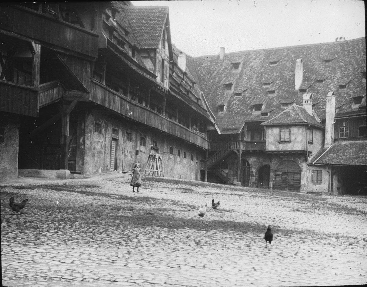 Skioptikonbild med motiv av den gotiska gården till Alte Hofhaltung, gamla domstolen i Bamberg.
Bilden har förvarats i kartong märkt: Resan 1906. Bamberg 8.