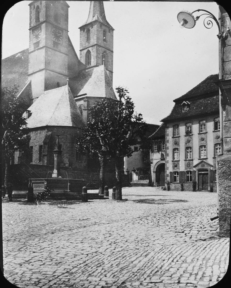 Skioptikonbild med motiv av torget vid St. Peters kirche, Bad Wimpfen.
Bilden har förvarats i kartong märkt: Resan 1907. Wimpfen 9. 01. Text på bild: "Wimpfen am Berg. Pfarrkirche".