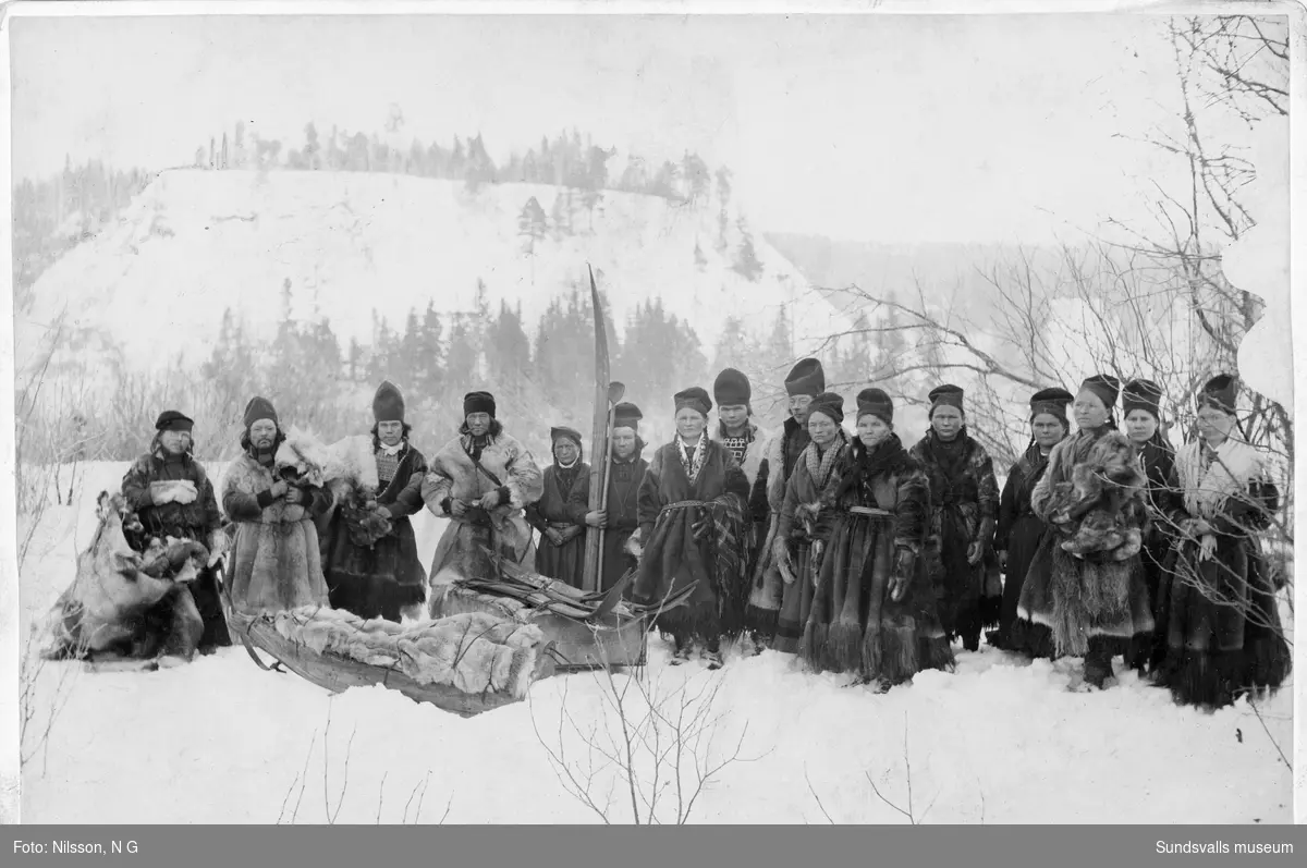 Gruppbild med samer, traditionellt klädda i renskinnspälsar. Okänt vart bilden är tagen. Troligen någonstans i inom Sollefteå kommun. Text i nedre kanten "Lappar N:r 36".