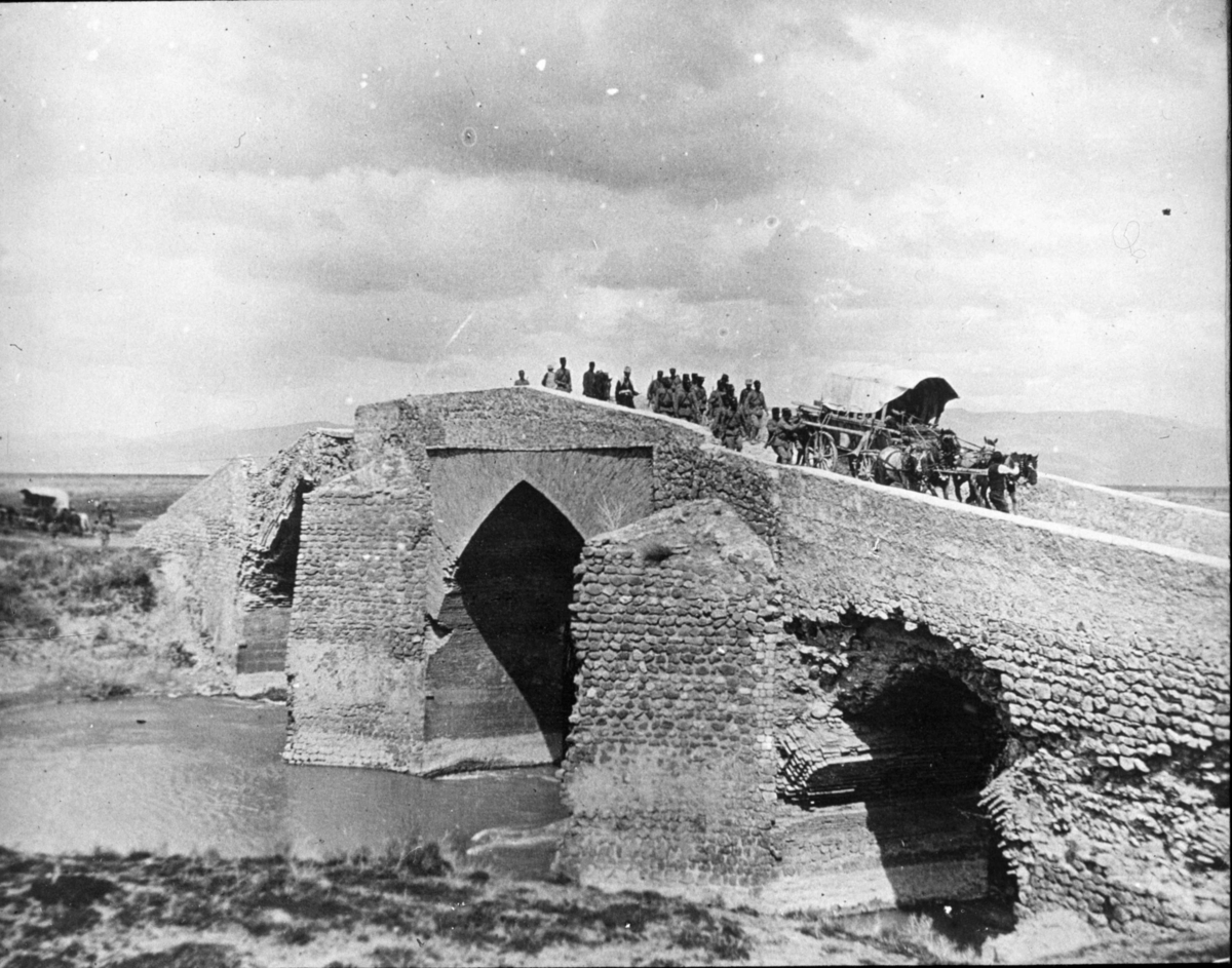"Passerandet af en bro. (Typisk brokonstruktion i Persien.) "Från Chiraz-expeditionen [Shiraz] i mars 1913" - kanske det ska vara 1912? Samling vid ett vattendrag.