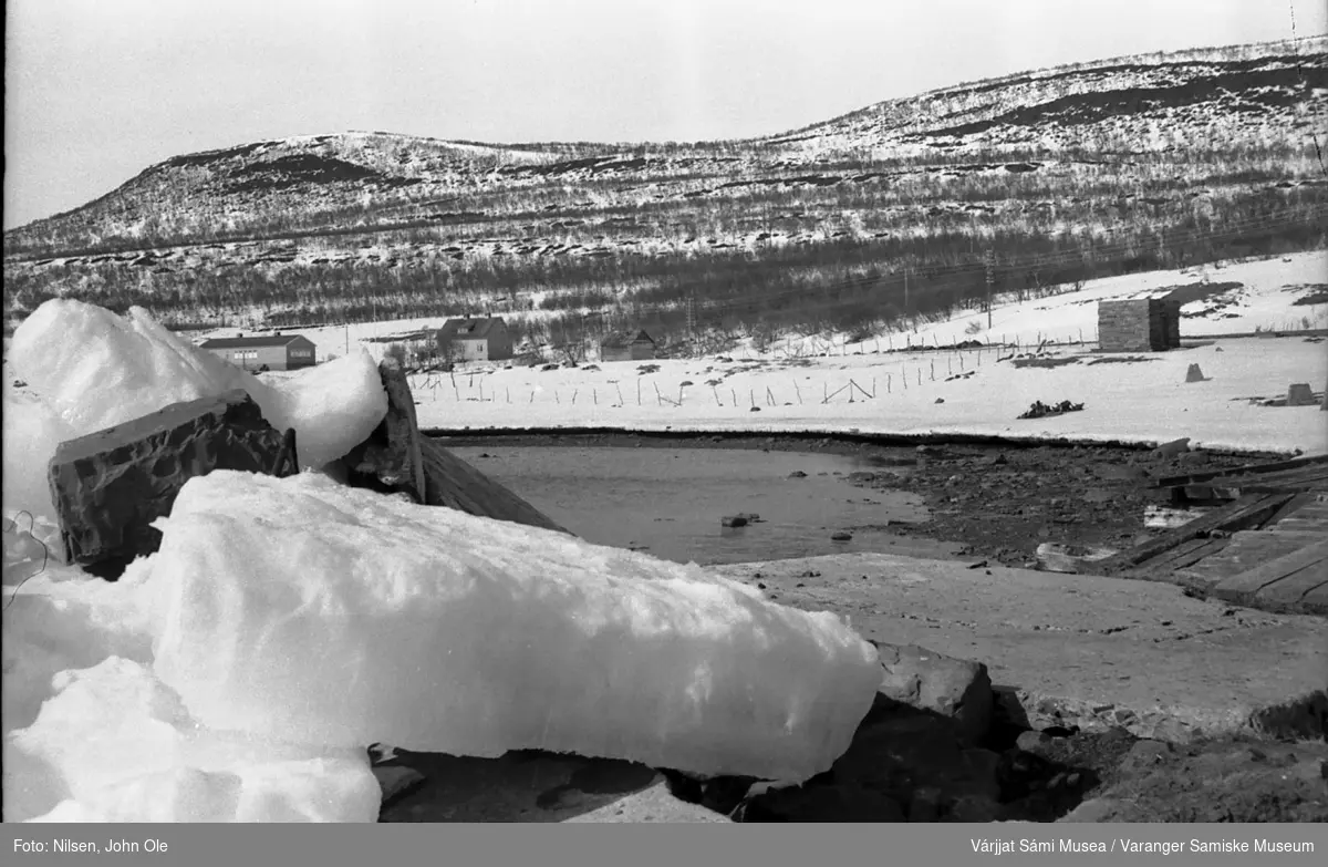 Kaia i Gornitak som er delvis brutt i stykker av fjordisen. Gamle Meskelv skole og lærerbolig med Aldon og Gornitakfjellet i bakgrunnen. 1967