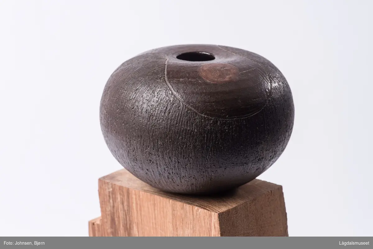 En geometrisk sirkel på ene siden i en annen bruntone inni en markert timeglassform på toppen av vasen er eneste motiv.
