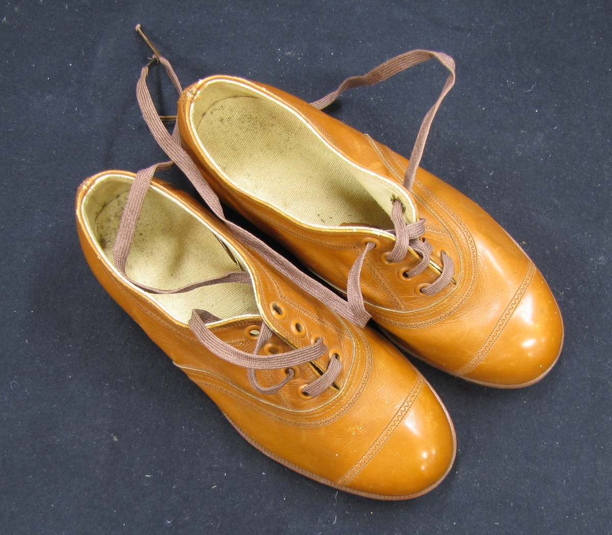 Ett par skor, barnskor, med snörning. Skorna är bruna och på sulans utsida är skorna märkta med A. F. Carlssons skofabriks sigill.