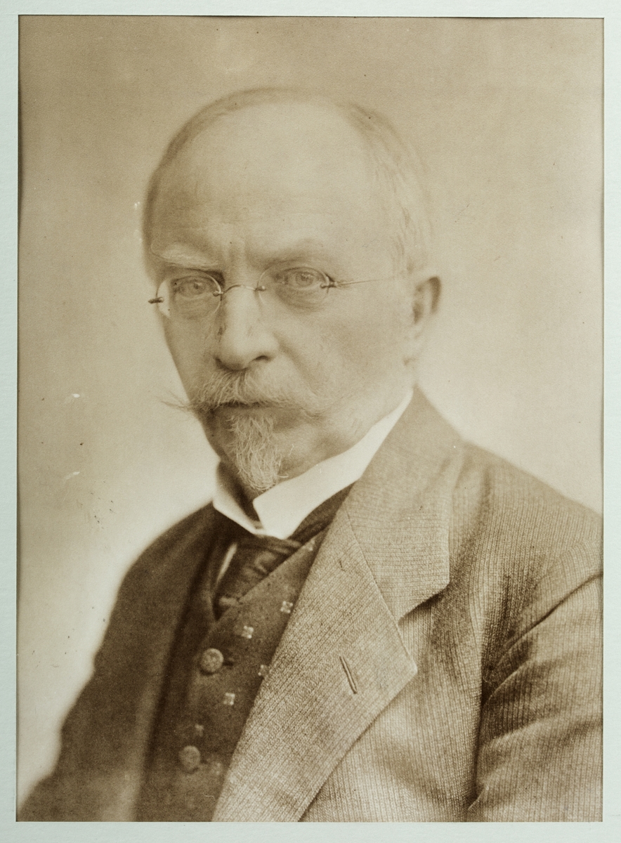 Svart- hvitt fotografisk portrett av en mann satt i glass og ramme.